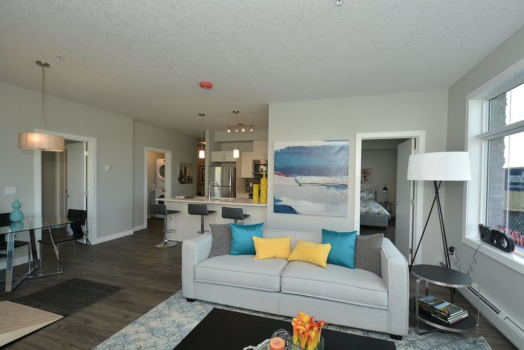 A living room with a grey couch and a painting on the wall.