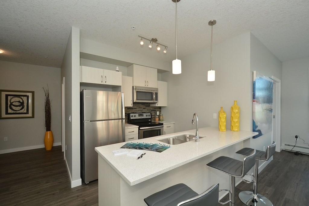 A modern kitchen with a white island and stainless steel appliances.