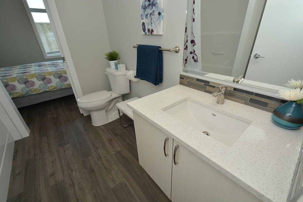 A bathroom with a toilet, sink, and mirror.