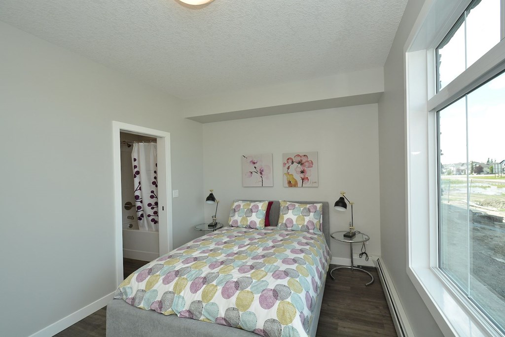 A bedroom with a bed, two lamps, and a painting on the wall.