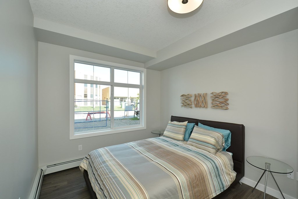 A bedroom with a bed, a window, and a wall hanging.