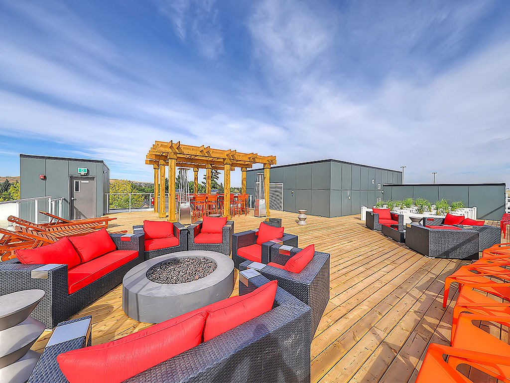 A wooden deck with red and black furniture and a fire pit.