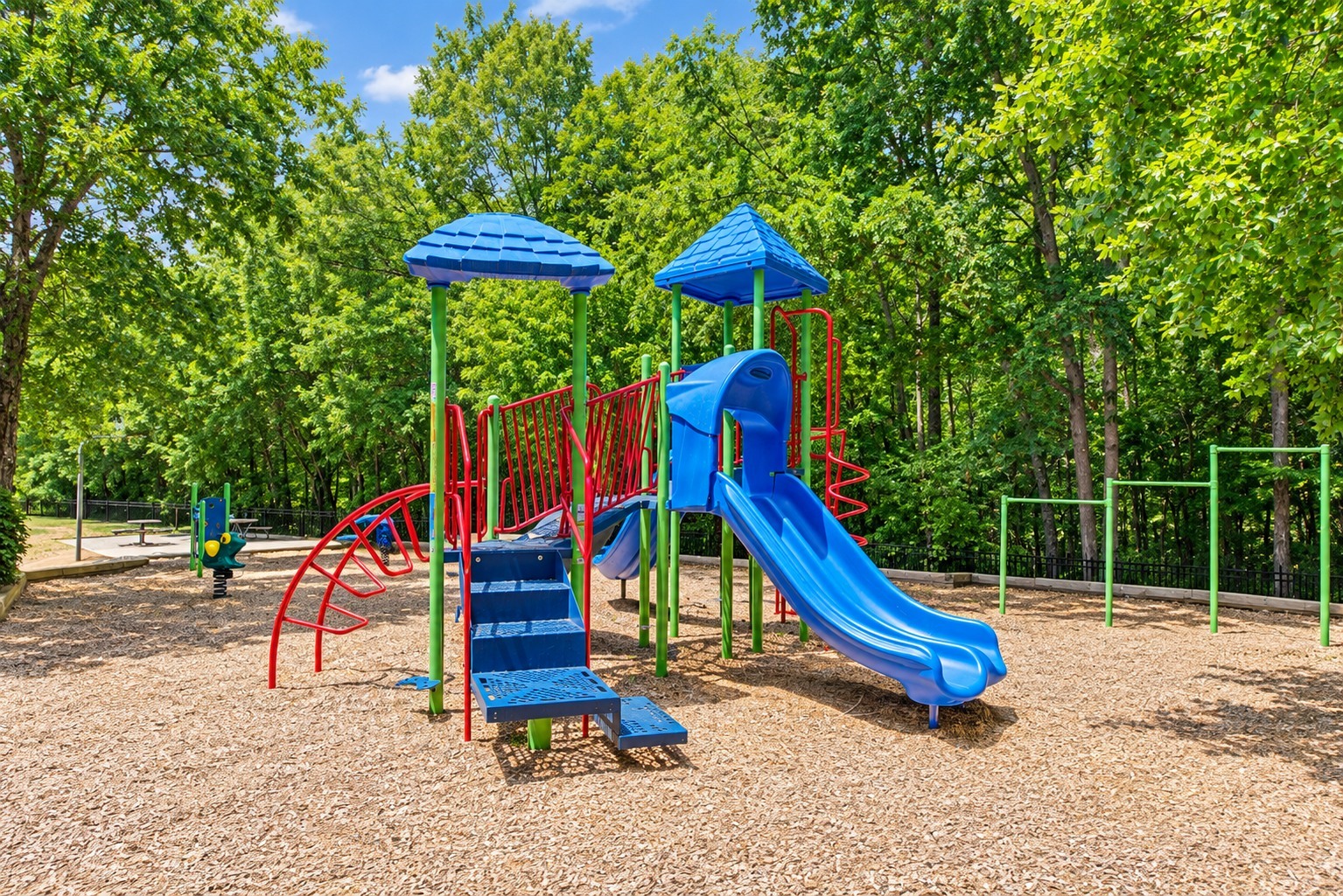 A playground with a blue slide and red and blue swings.