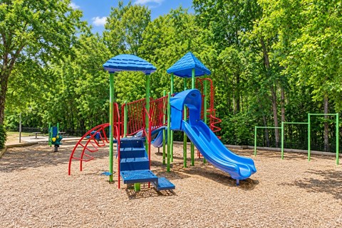 A playground with a blue slide and red and blue swings.