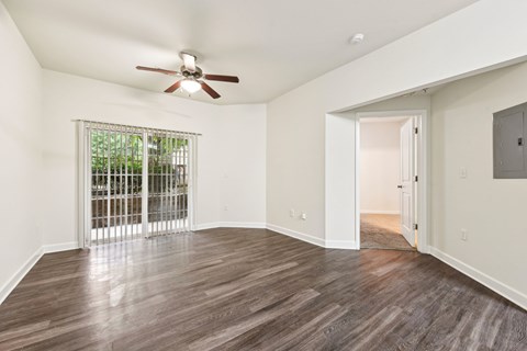 A room with a ceiling fan and sliding glass doors.