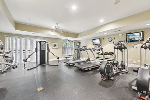 A spacious gym with a variety of equipment including treadmills, elliptical machines, and weight machines.