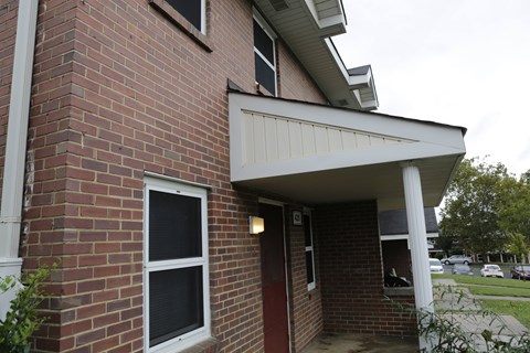 A red brick house with a white door and window.