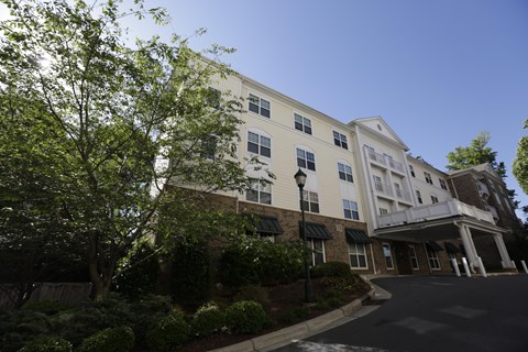 A large white building with a black awning and a tree in front of it.