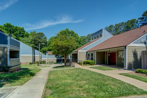 A sunny day at a residential complex with green lawns and trees.