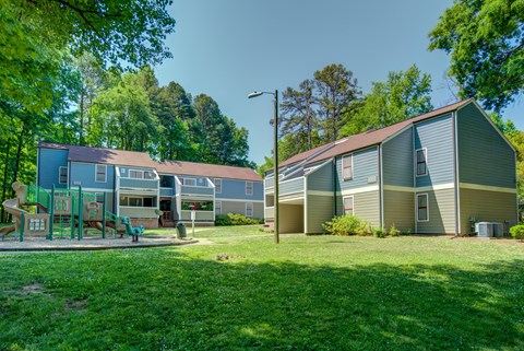 A playground area is located in front of a building with a green lawn.