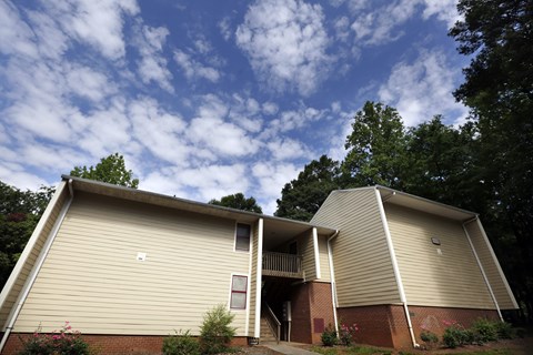 A beige building with a red brick base and a balcony on the second floor.