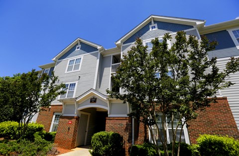 A two-story house with a red brick base and a grey upper section with white trim.