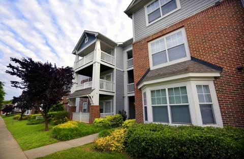 A two-story brick building with a balcony and a small porch.