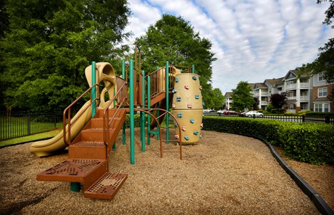 A playground with a slide, climbing wall, and a tunnel.