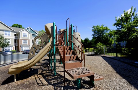 A playground with a yellow slide and a brown climbing structure.
