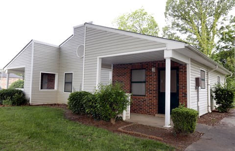 A small house with a white siding and a brick chimney.