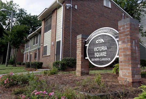 A sign for Victoria Square is in front of a brick building.