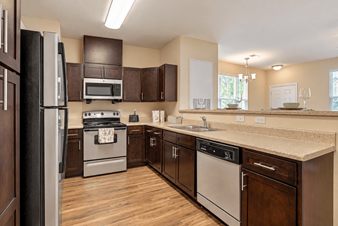 A kitchen with a black refrigerator and wooden cabinets.