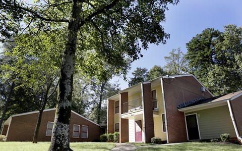 A tree stands in front of a house with a balcony.