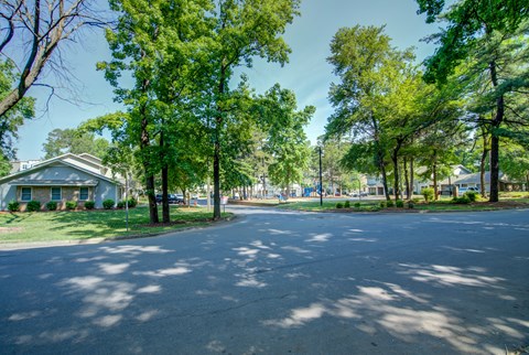 A tree-lined street with a house on the left.