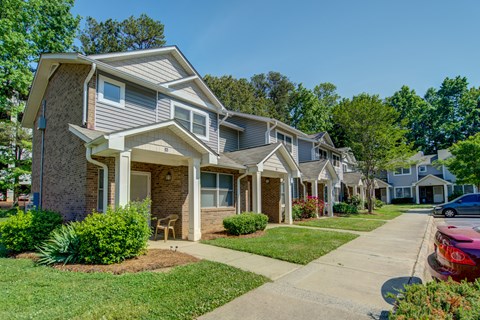 A row of houses with a red car parked in front of the first house.
