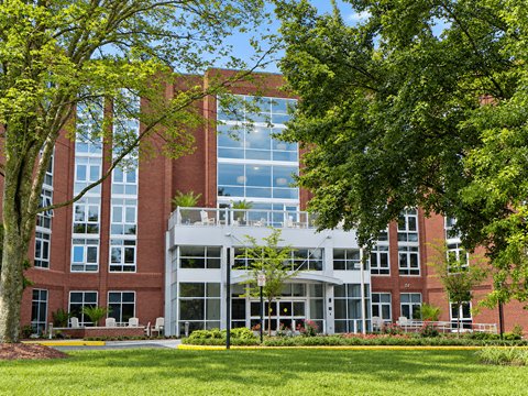A large red brick building with a green lawn in front.