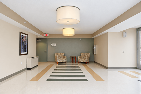 A hallway with a striped rug and two chairs.