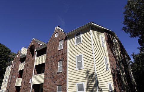A tall apartment building with a red brick base and beige siding.