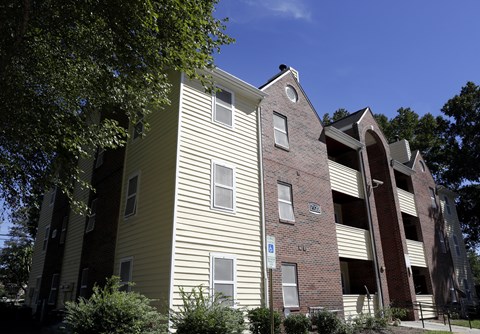 A building with a yellow siding and a brick section with a white sign on it.