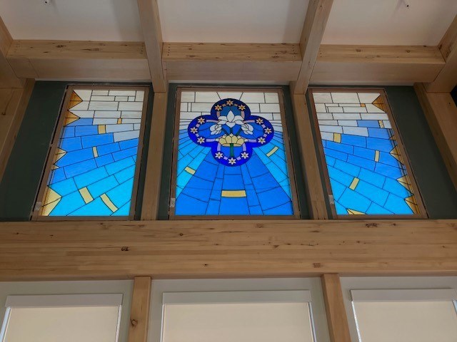 Three stained glass windows in a wooden frame.