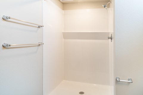 A white bathroom with a toilet and a shower.at All Saints Apartments, DENVER