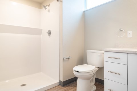 A white toilet sits next to a white sink in a bathroom at All Saints Apartments, DENVER, Colorado