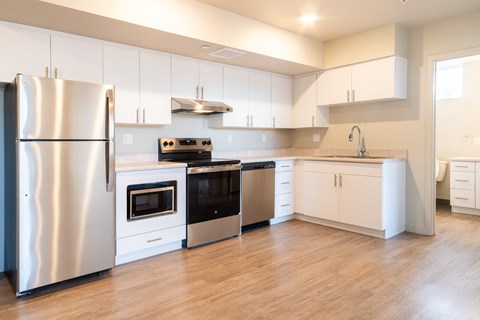 A modern kitchen with a stainless steel refrigerator and white cabinets.