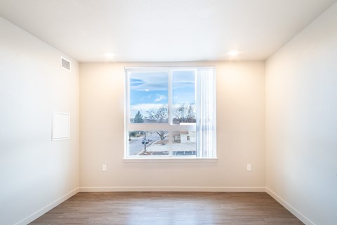 A room with a large window showing a snowy landscape outside. at All Saints Apartments, DENVER, CO