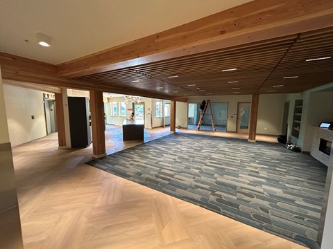 A spacious room with wooden floors and a carpeted area.