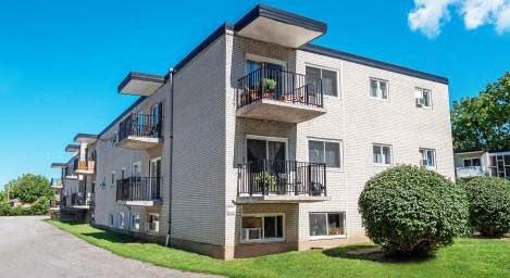 A modern apartment building with balconies and green bushes in front.