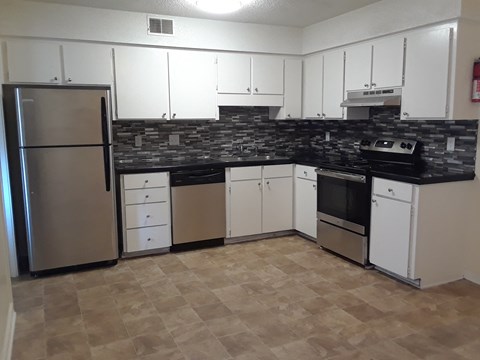 A kitchen with a refrigerator, oven, and microwave.
