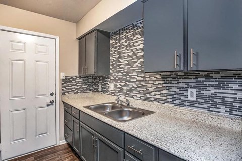 A kitchen with a sink and a white door.