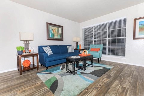 A living room with a blue couch and a table with a lamp on it.