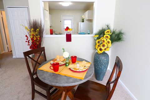 a dining area with a table and chairs and a vase of flowers