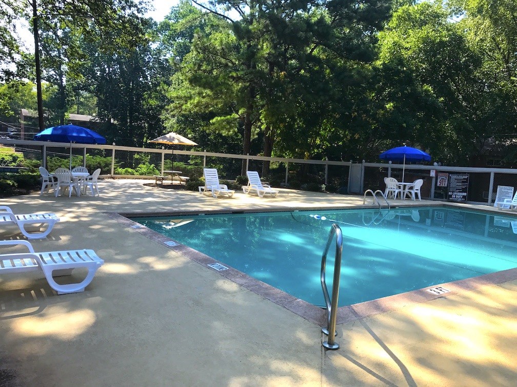 a swimming pool with chairs and umbrellas around it