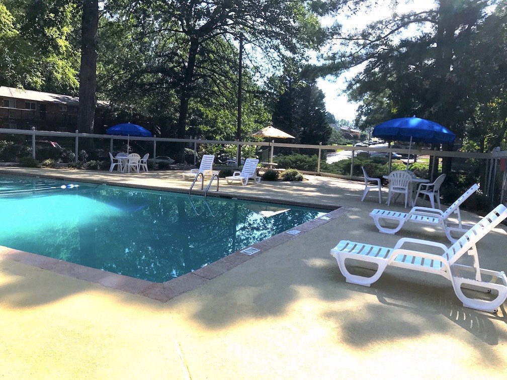 a swimming pool with chairs and umbrellas around it