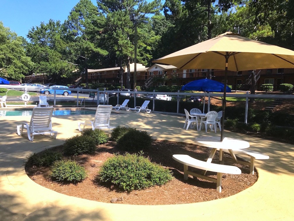a patio with tables and umbrellas next to a pool