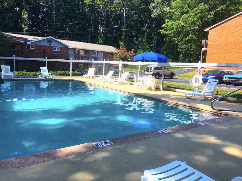 a swimming pool with chairs around it next to a house
