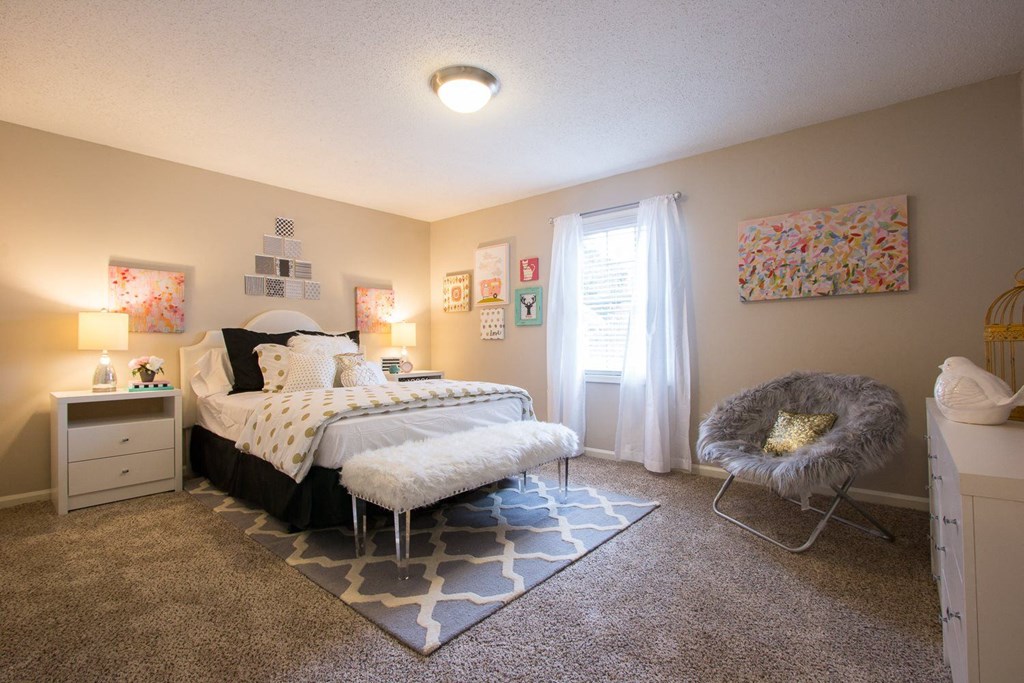 a bedroom with a bed and a chair and a window