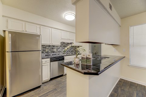 A kitchen with a stainless steel refrigerator and a granite countertop.