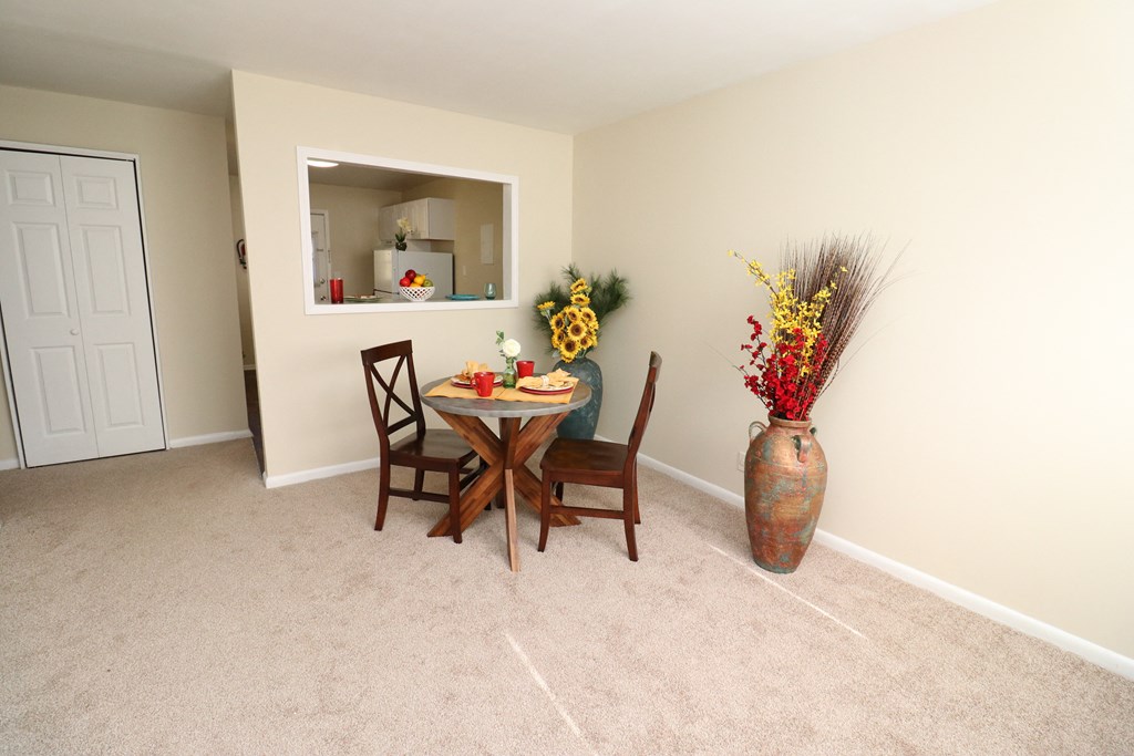 a dining room with a table and chairs and a vase with flowers
