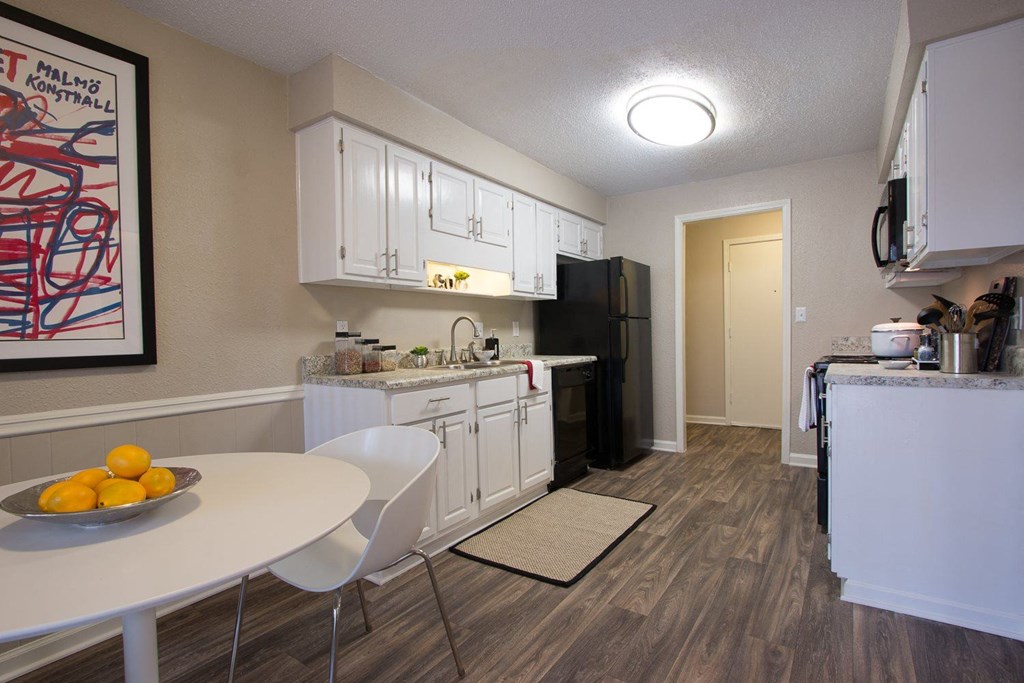 a kitchen and dining room with white cabinets and a black refrigerator