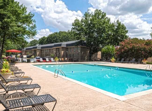 a swimming pool with benches and chairs around it