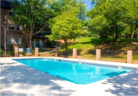 A swimming pool surrounded by a fence and trees.
